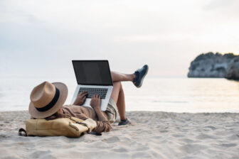 Young woman using laptop computer on beach, freelancer girl work